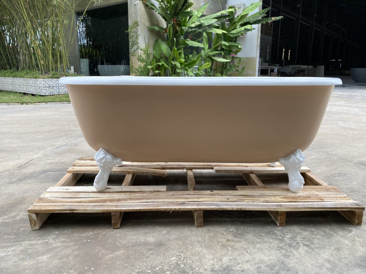 Beige solid surface freestanding bathtub facing garden view, natural spa style.